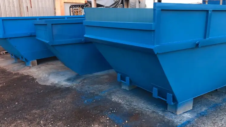 Serie de contenedores de obra azules recién pintados