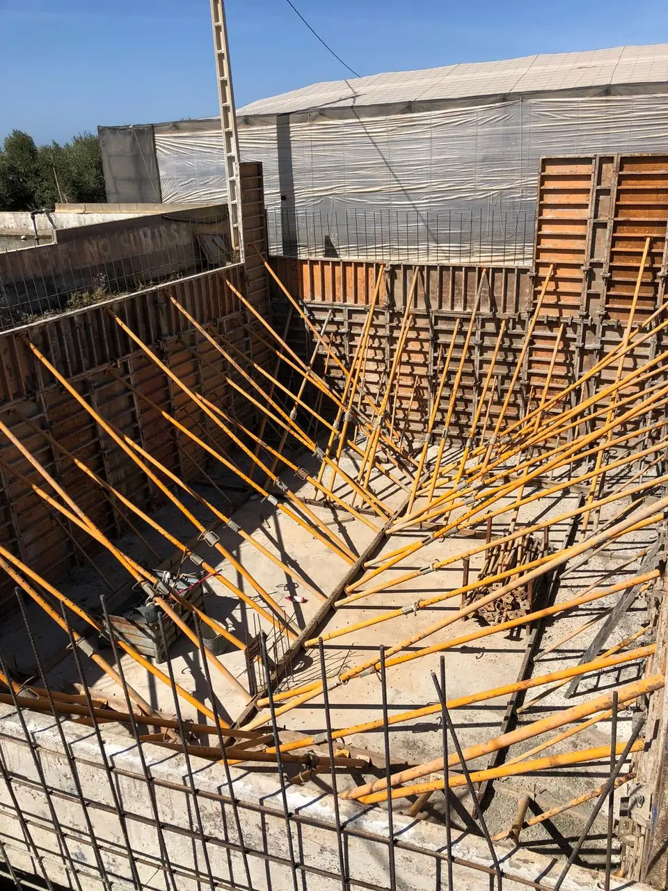 Encofrado metálico de los muros de un aljibe junto a invernaderos