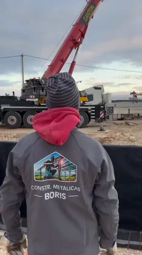Operario de Construcciones Metálicas Boris con la chaqueta de la empresa durante un montaje con grúa