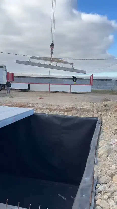 Grúa bajando una placa alveolar de hormigón para cubrir un aljibe